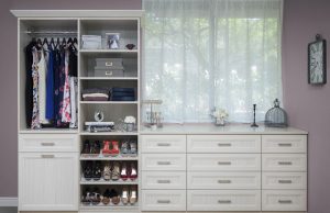 White closet system with shelving and drawers underneath window